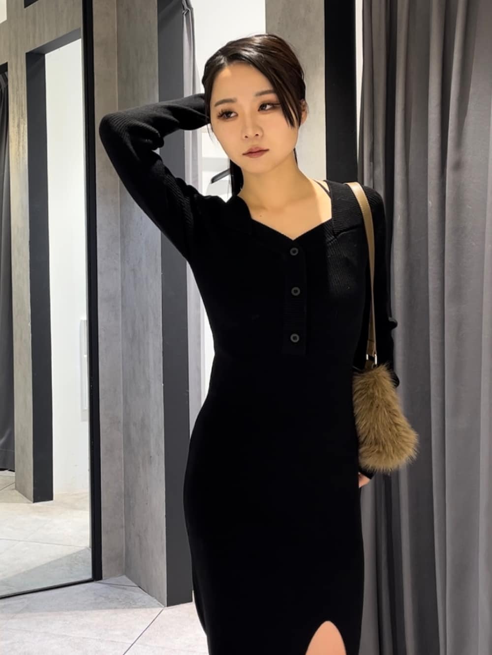 ブラック系のワンピース、ベージュ系のショルダーバッグ、ブラック系のブーツを着用したレディースの冬コーディネートの6枚目の写真