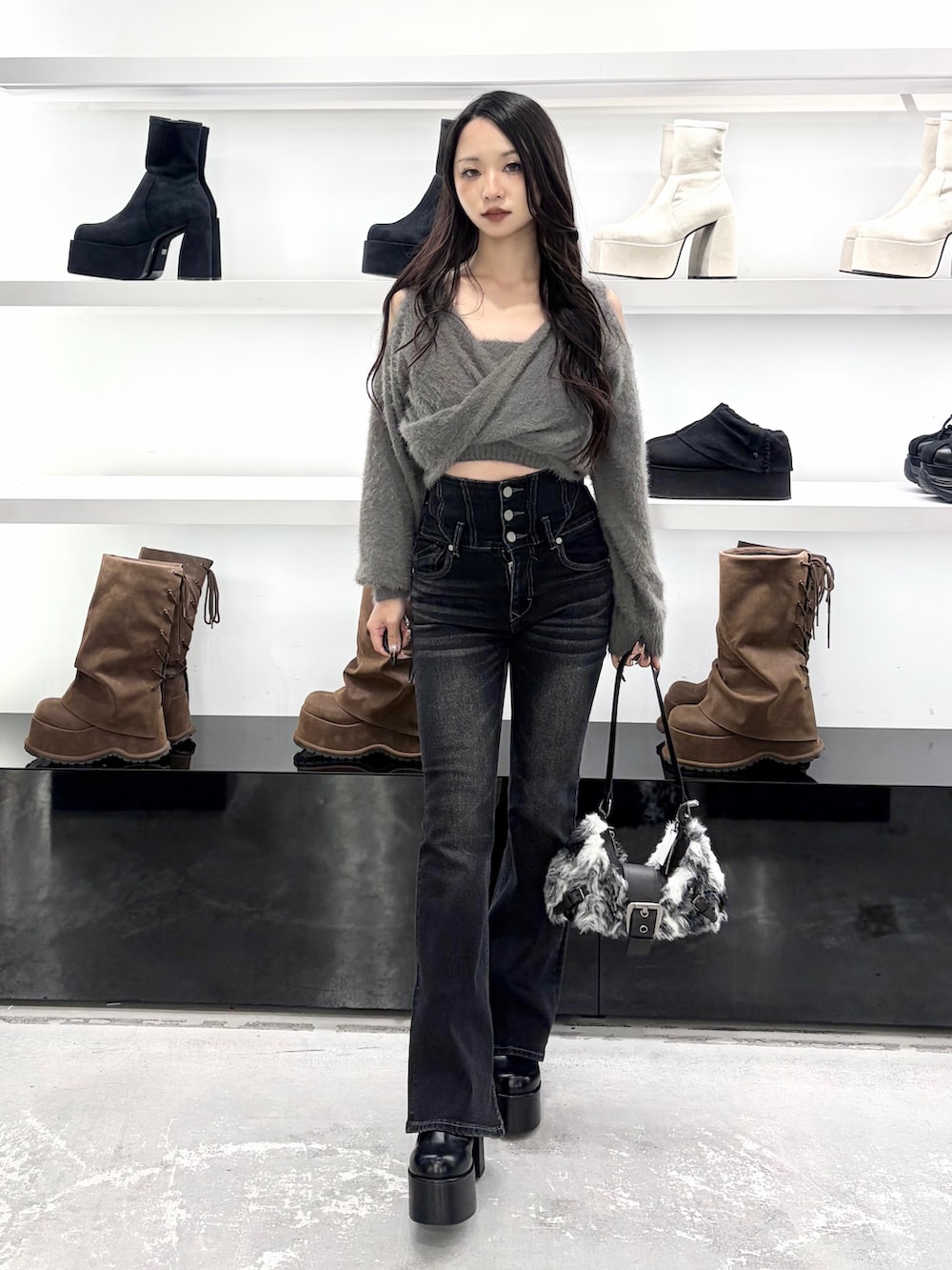 グレー系のニット/セーター、ブラック系のデニムパンツ、ブラック系のショルダーバッグを着用したレディースの秋コーディネートの2枚目の写真