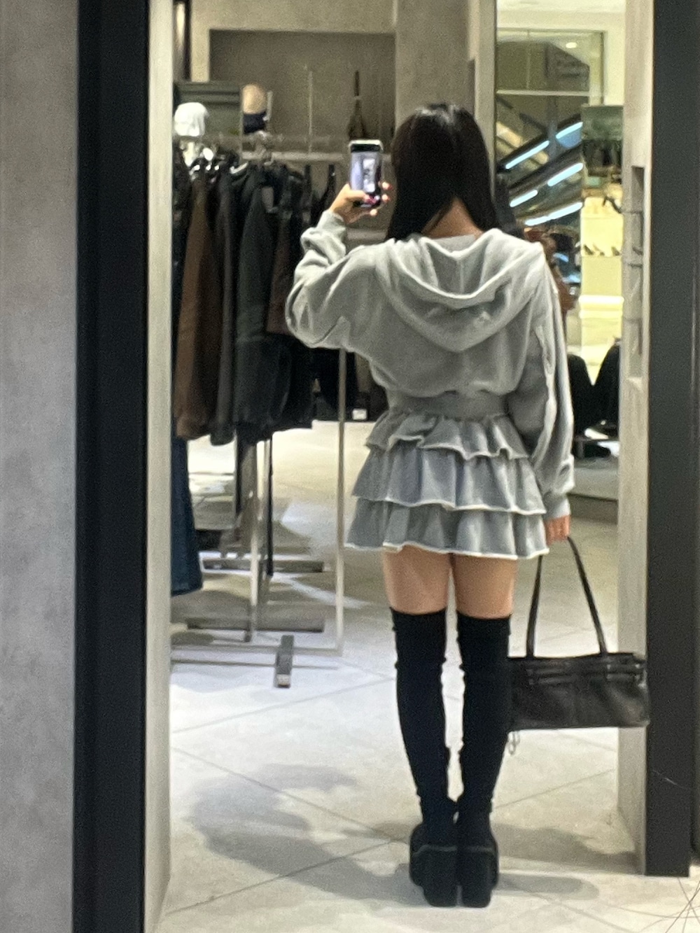 グレー系のパーカー、グレー系のスカート、ブラック系のショルダーバッグを着用したレディースの秋コーディネートの4枚目の写真
