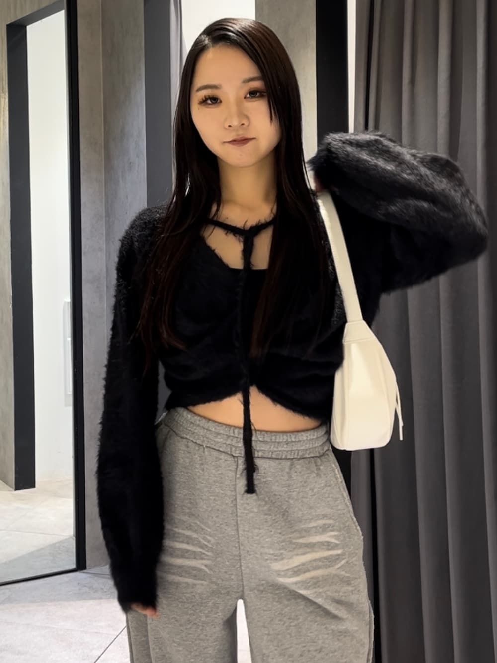 ブラック系のニット/セーター、グレー系のスウェットパンツ、ホワイト系のショルダーバッグを着用したレディースの冬コーディネートの5枚目の写真