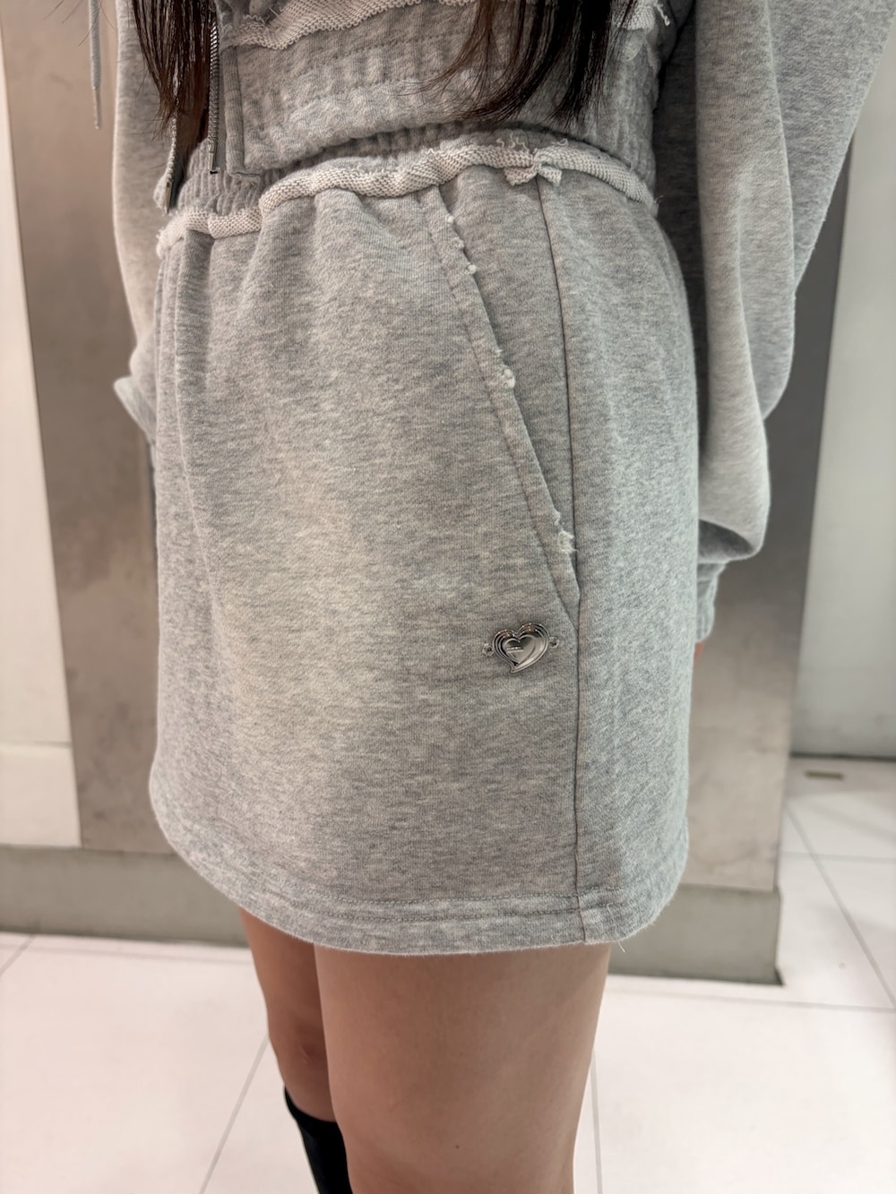 グレー系のTシャツ/カットソー、グレー系のスカート、ブラック系のブーツを着用したレディースの秋コーディネートの7枚目の写真