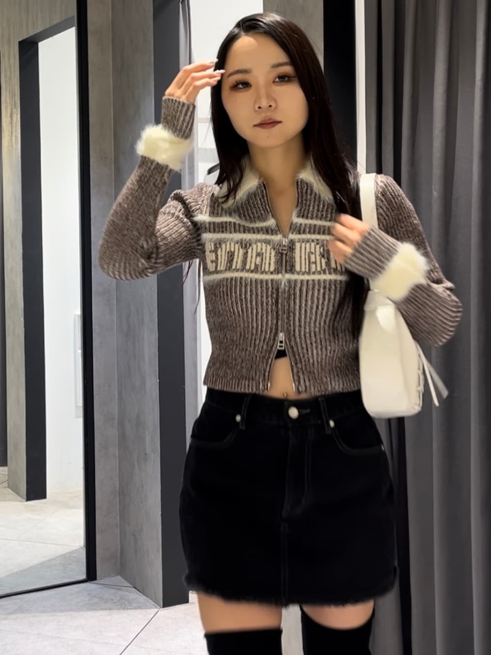 ブラウン系のニット/セーター、ブラック系のスカート、ホワイト系のショルダーバッグを着用したレディースの冬コーディネートの4枚目の写真