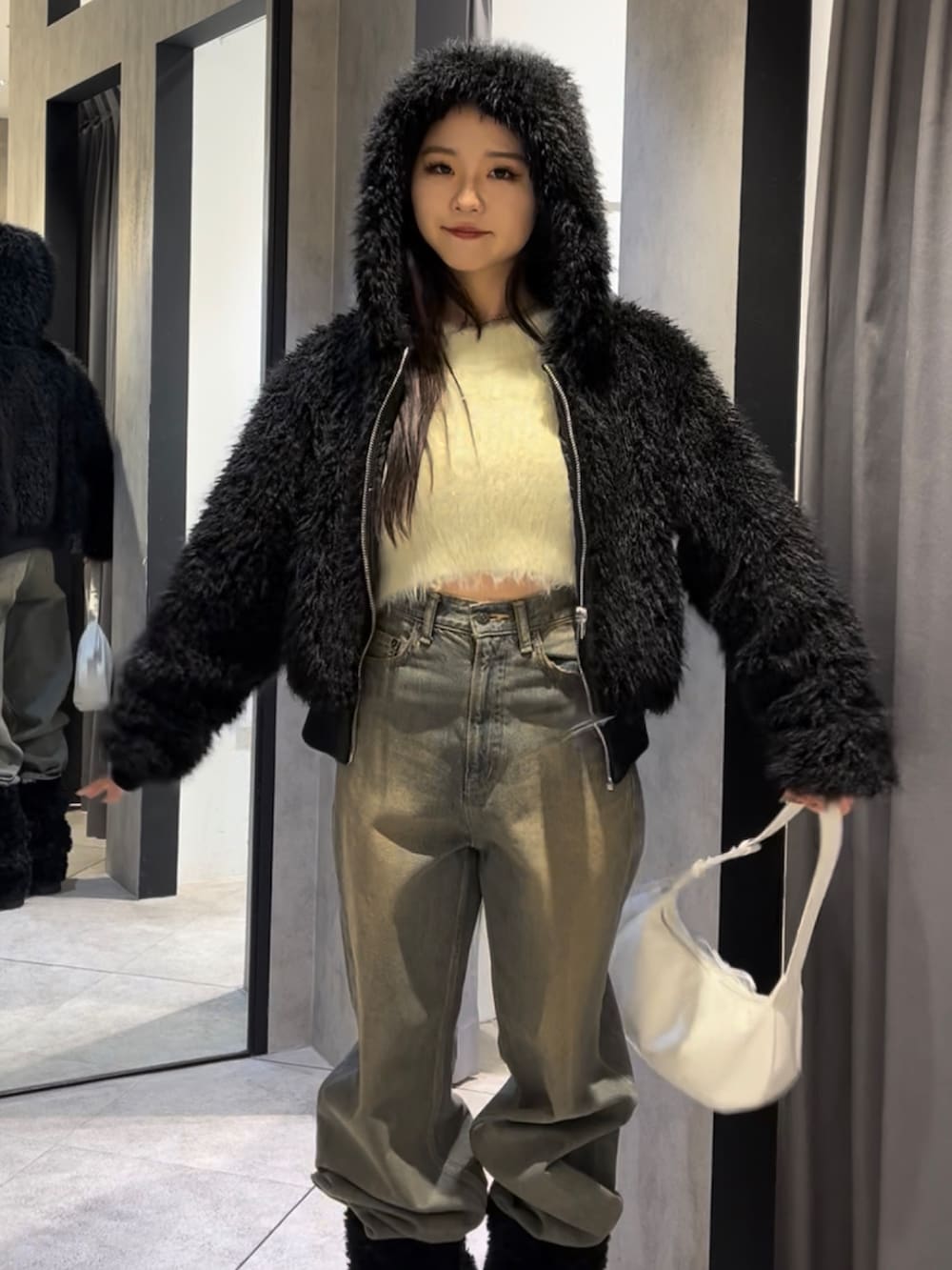 ブラック系のブルゾン、ホワイト系のニット/セーター、ブルー系のデニムパンツを着用したレディースの冬コーディネートの10枚目の写真