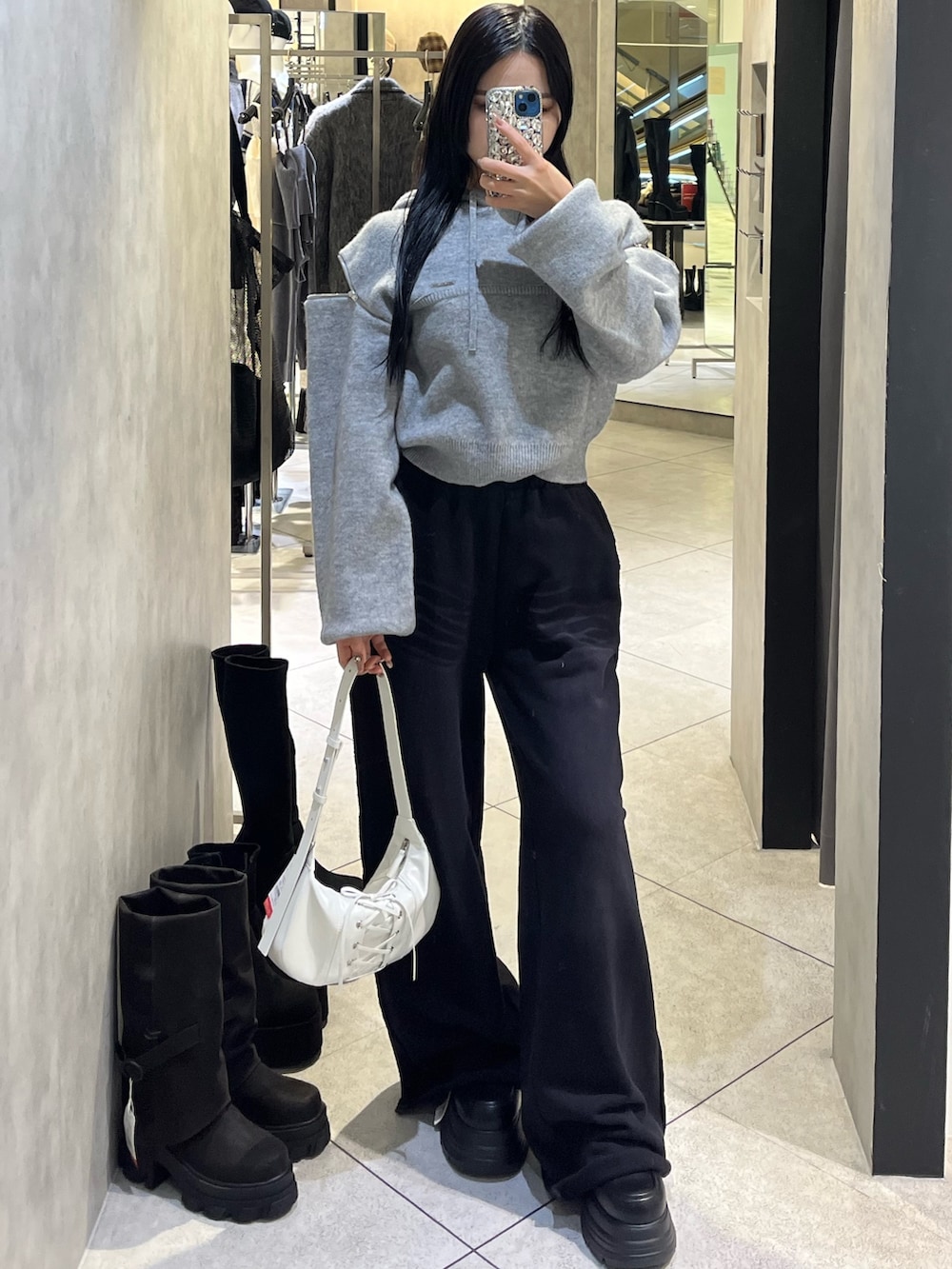 グレー系のパーカー、ブラック系のローファー、ホワイト系のショルダーバッグを着用したレディースの冬コーディネートの2枚目の写真