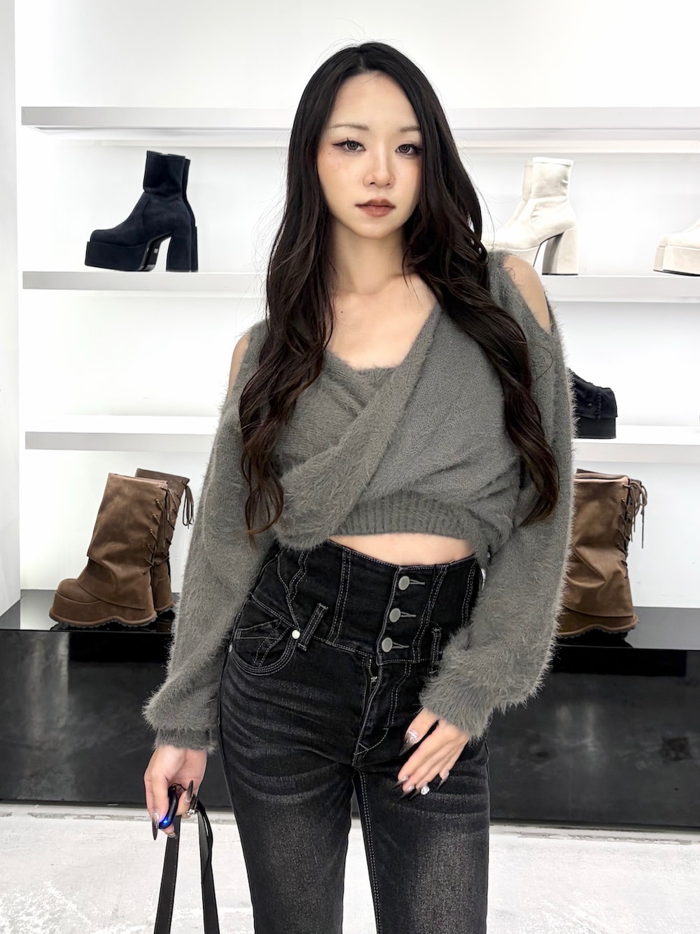 グレー系のニット/セーター、ブラック系のデニムパンツ、ブラック系のショルダーバッグを着用したレディースの秋コーディネートの7枚目の写真
