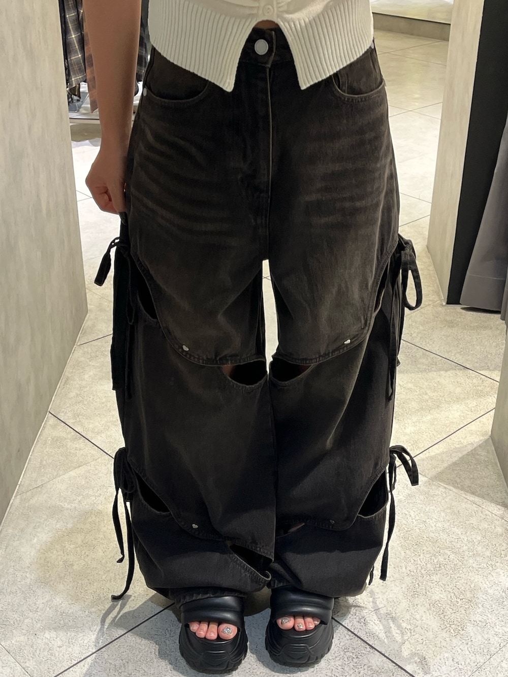 ホワイト系のニット/セーター、ブラック系のデニムパンツ、ブラック系のサンダルを着用したレディースの秋コーディネートの5枚目の写真