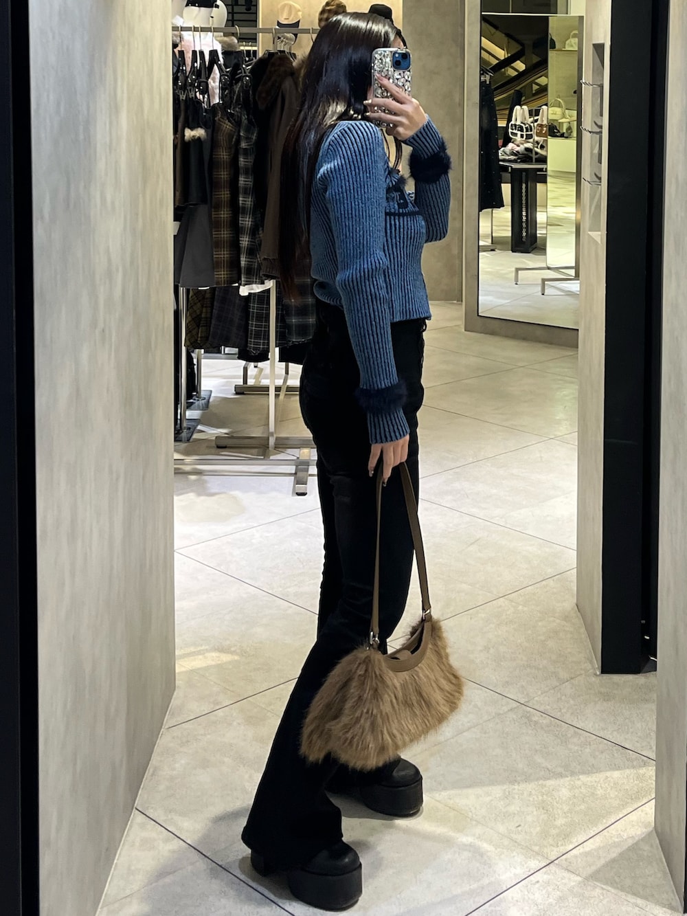ブルー系のニット/セーター、ブラック系のデニムパンツ、ベージュ系のショルダーバッグを着用したレディースの冬コーディネートの2枚目の写真