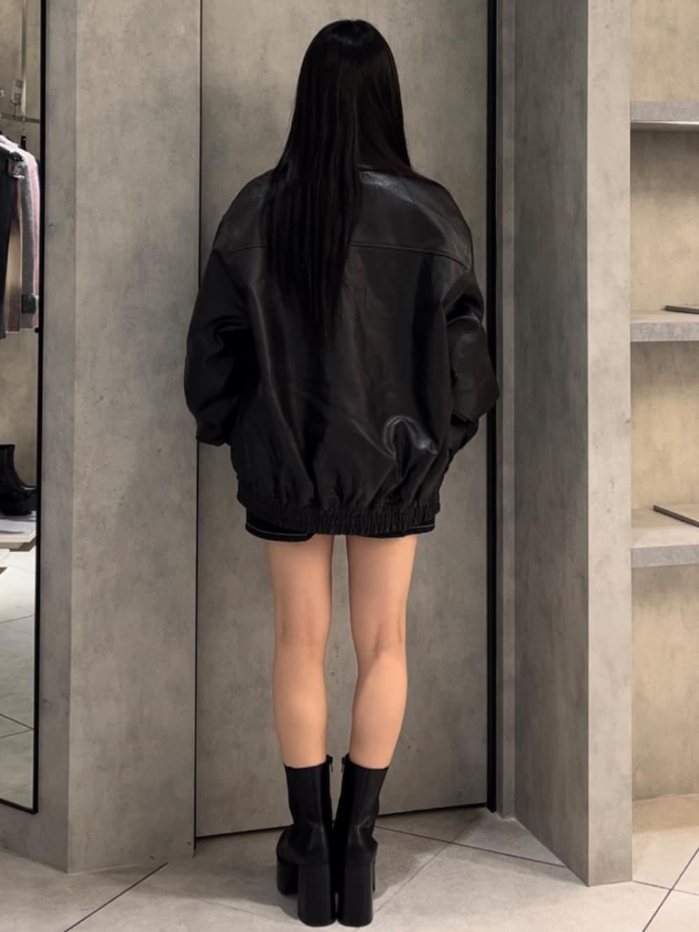 ブラック系のブルゾン、ピンク系のTシャツ/カットソー、ブルー系のスカートを着用したレディースの冬コーディネートの3枚目の写真