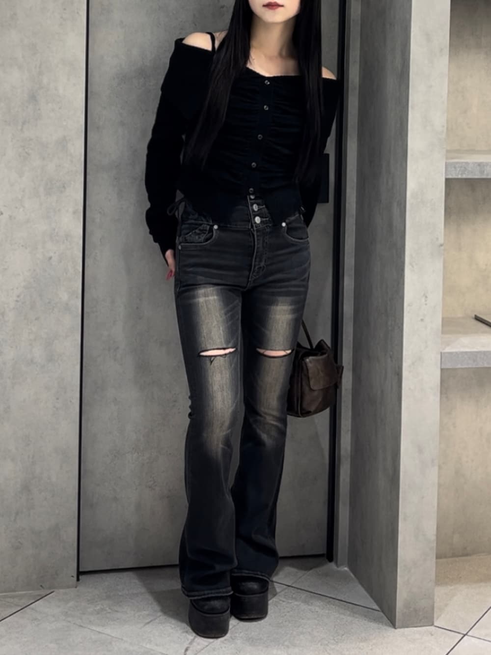 ブラック系のニット/セーター、ブラック系のデニムパンツ、ブラウン系のハンドバッグを着用したレディースの冬コーディネートの10枚目の写真