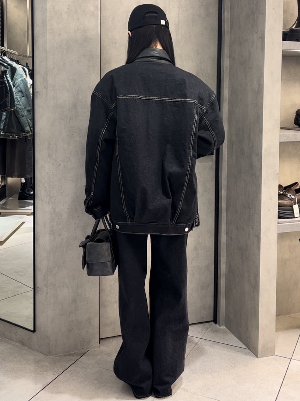 ブルー系のブルゾン、ブルー系のデニムパンツ、ブラック系のハンドバッグを着用したレディースの冬コーディネートの3枚目の写真