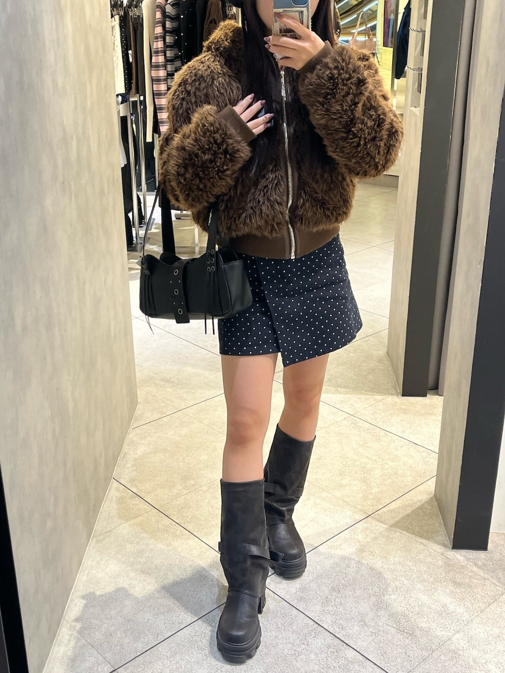 ブラック系のブーツ、ブラック系のハンドバッグ、ブルー系のスカートを着用したレディースの秋コーディネートの5枚目の写真