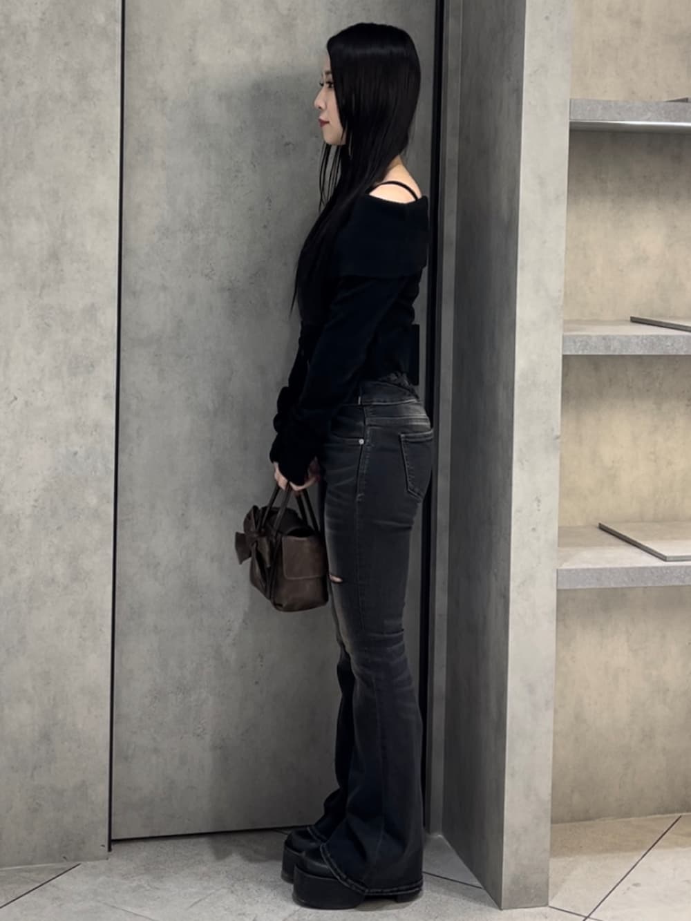 ブラック系のニット/セーター、ブラック系のデニムパンツ、ブラウン系のハンドバッグを着用したレディースの冬コーディネートの3枚目の写真