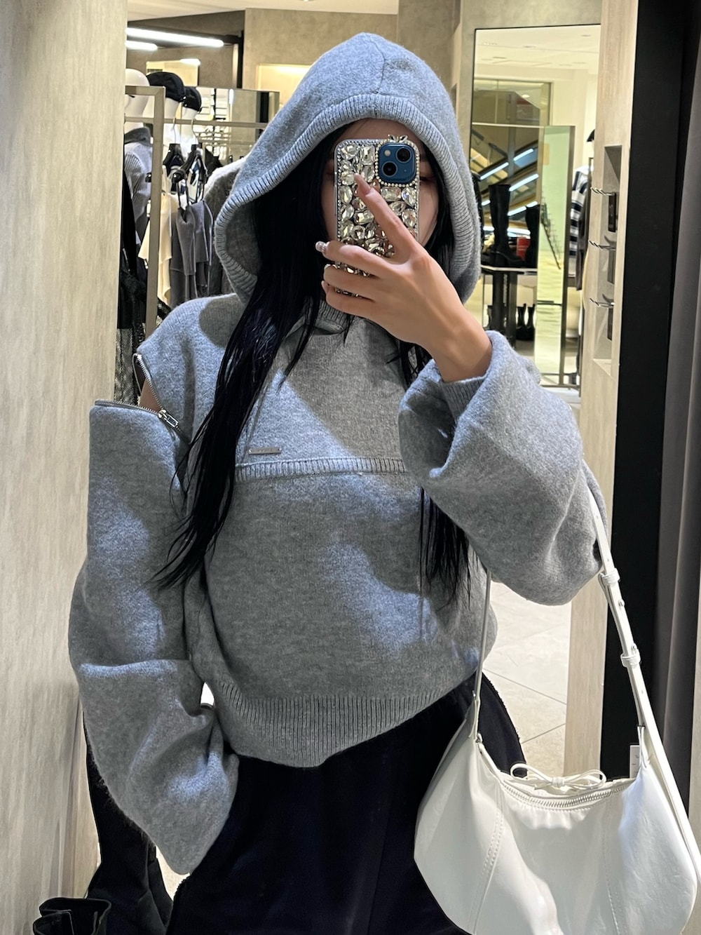 グレー系のパーカー、ブラック系のローファー、ホワイト系のショルダーバッグを着用したレディースの冬コーディネートの5枚目の写真