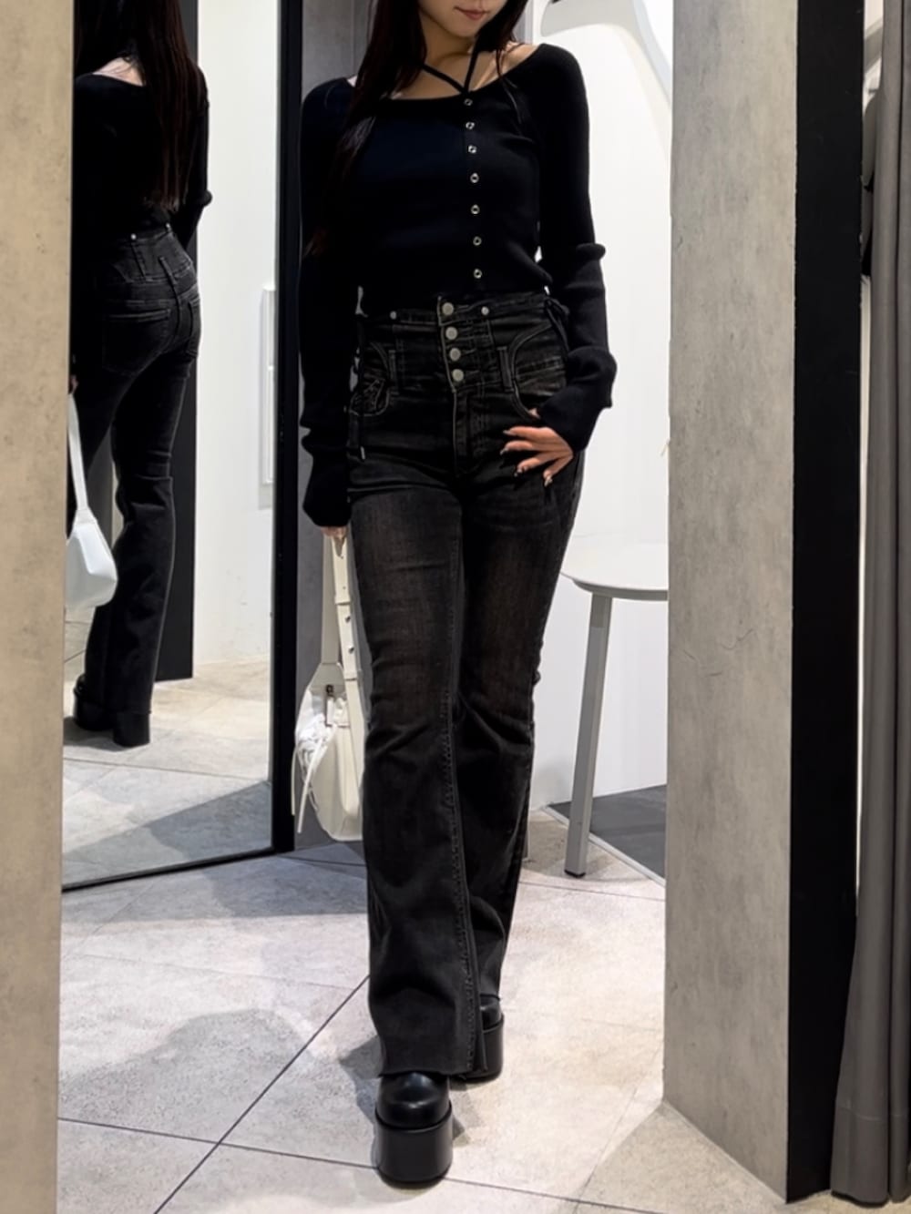 ブラック系のニット/セーター、ブラック系のデニムパンツ、ホワイト系のショルダーバッグを着用したレディースの冬コーディネートの2枚目の写真