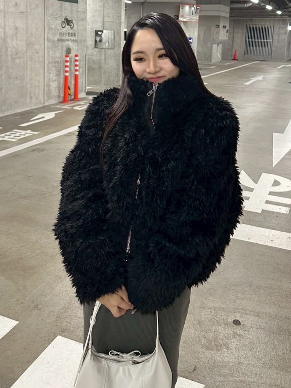 ブラック系のブルゾン、グレー系のワンピース、ホワイト系のショルダーバッグを着用したレディースの冬コーディネートの6枚目の写真