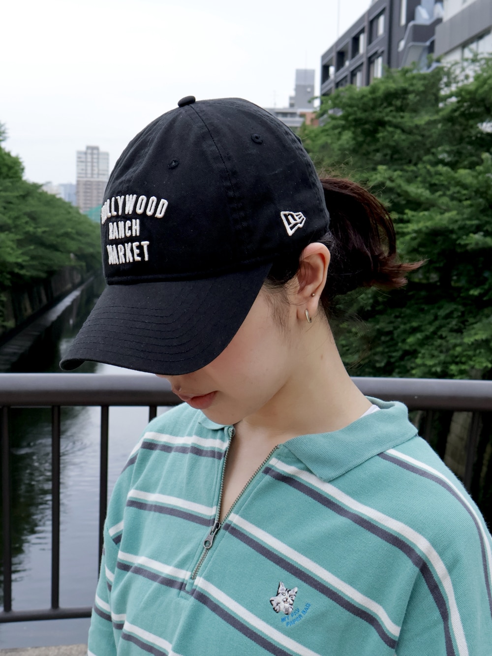 グリーン系のポロシャツ、ホワイト系のスニーカー、ブルー系のデニムパンツを着用したレディースの春コーディネートの2枚目の写真