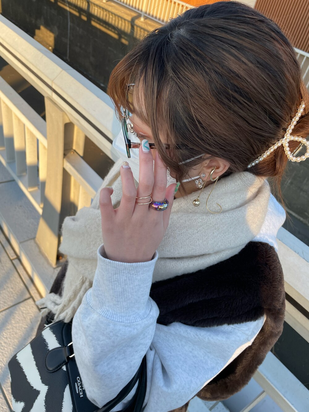 グレー系のパーカー、ブラウン系のダウンベスト、ホワイト系のショルダーバッグを着用したレディースの冬コーディネートの2枚目の写真