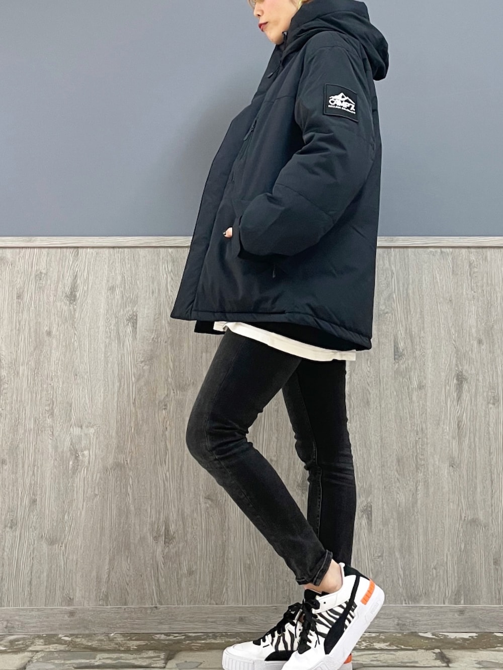 ブラック系のデニムパンツ、ブラック系のダウンジャケット/コート、ホワイト系のTシャツ/カットソーを着用したレディースの秋コーディネートの2枚目の写真