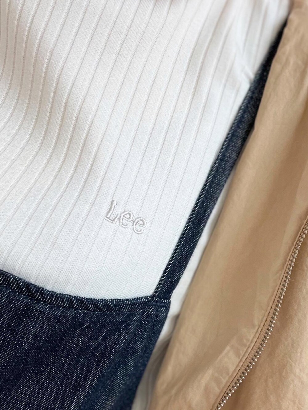 グレー系のショルダーバッグ、ベージュ系のマウンテンパーカー、ブルー系のサロペット/オーバーオールを着用したレディースの春コーディネートの5枚目の写真