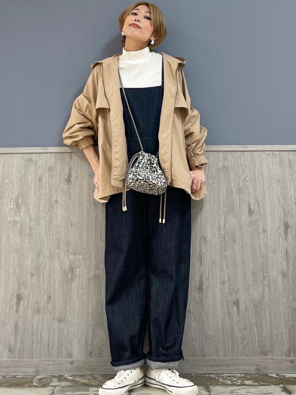 グレー系のショルダーバッグ、ベージュ系のマウンテンパーカー、ブルー系のサロペット/オーバーオールを着用したレディースの春コーディネートの4枚目の写真