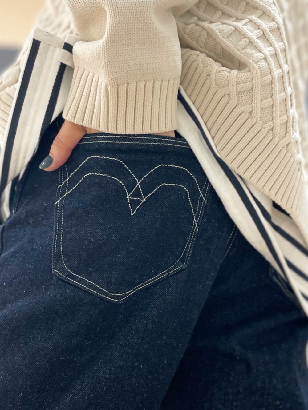 ブルー系のデニムパンツ、ホワイト系のニット/セーター、ベージュ系のトートバッグを着用したレディースの秋コーディネートの4枚目の写真