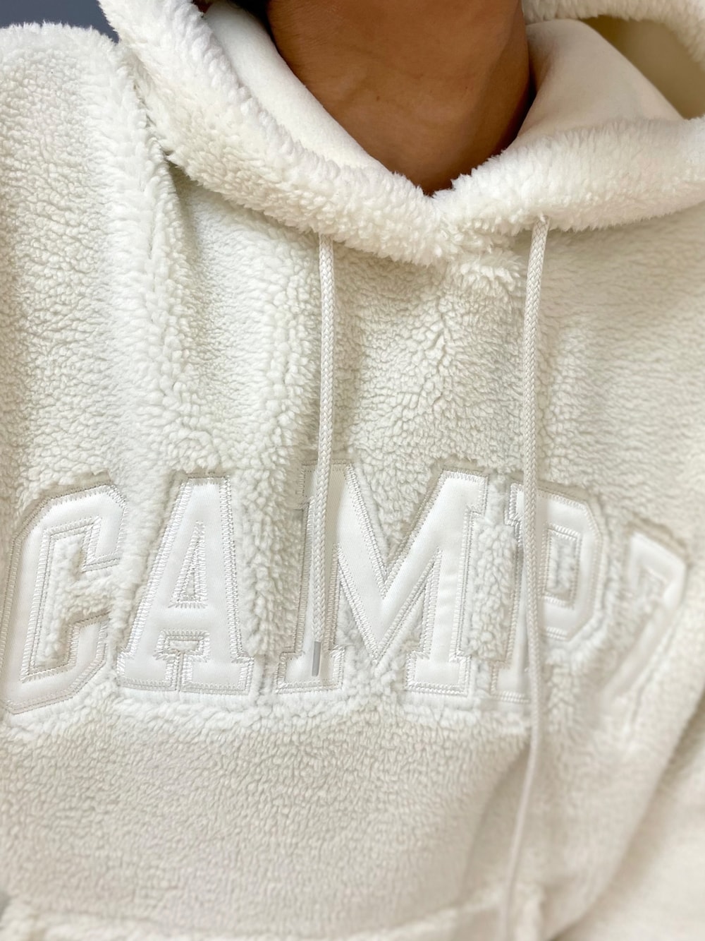 ブルー系のデニムパンツ、ブラウン系のショルダーバッグ、ホワイト系のパーカーを着用したレディースの冬コーディネートの5枚目の写真