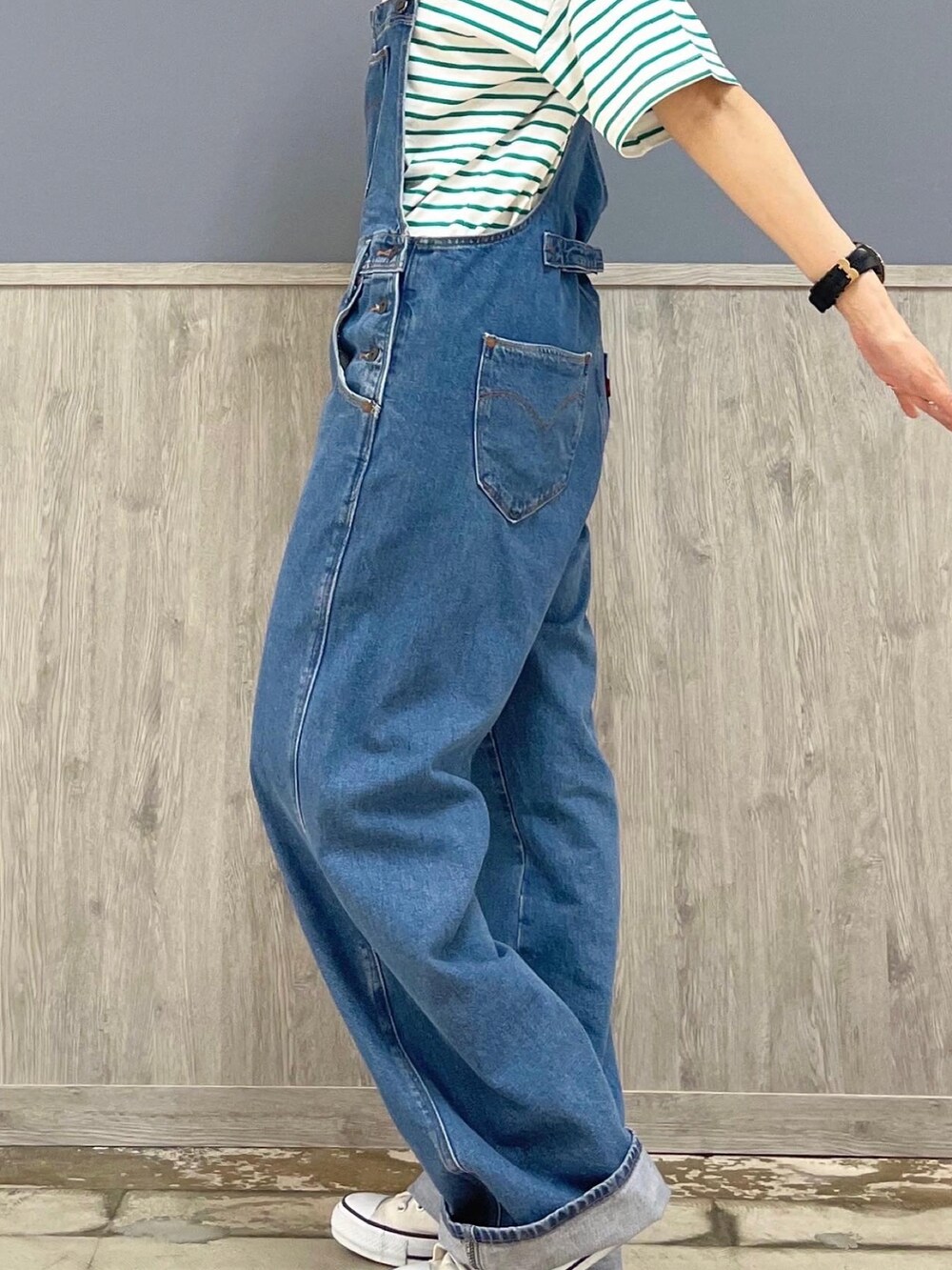ブルー系のサロペット/オーバーオール、ベージュ系のトートバッグ、グリーン系のTシャツ/カットソーを着用したレディースの夏コーディネートの2枚目の写真
