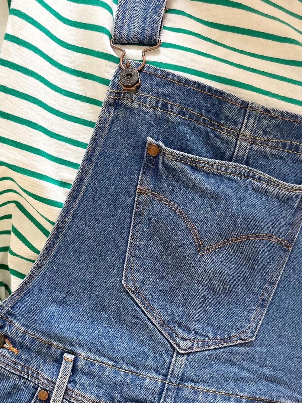ブルー系のサロペット/オーバーオール、ベージュ系のトートバッグ、グリーン系のTシャツ/カットソーを着用したレディースの夏コーディネートの5枚目の写真