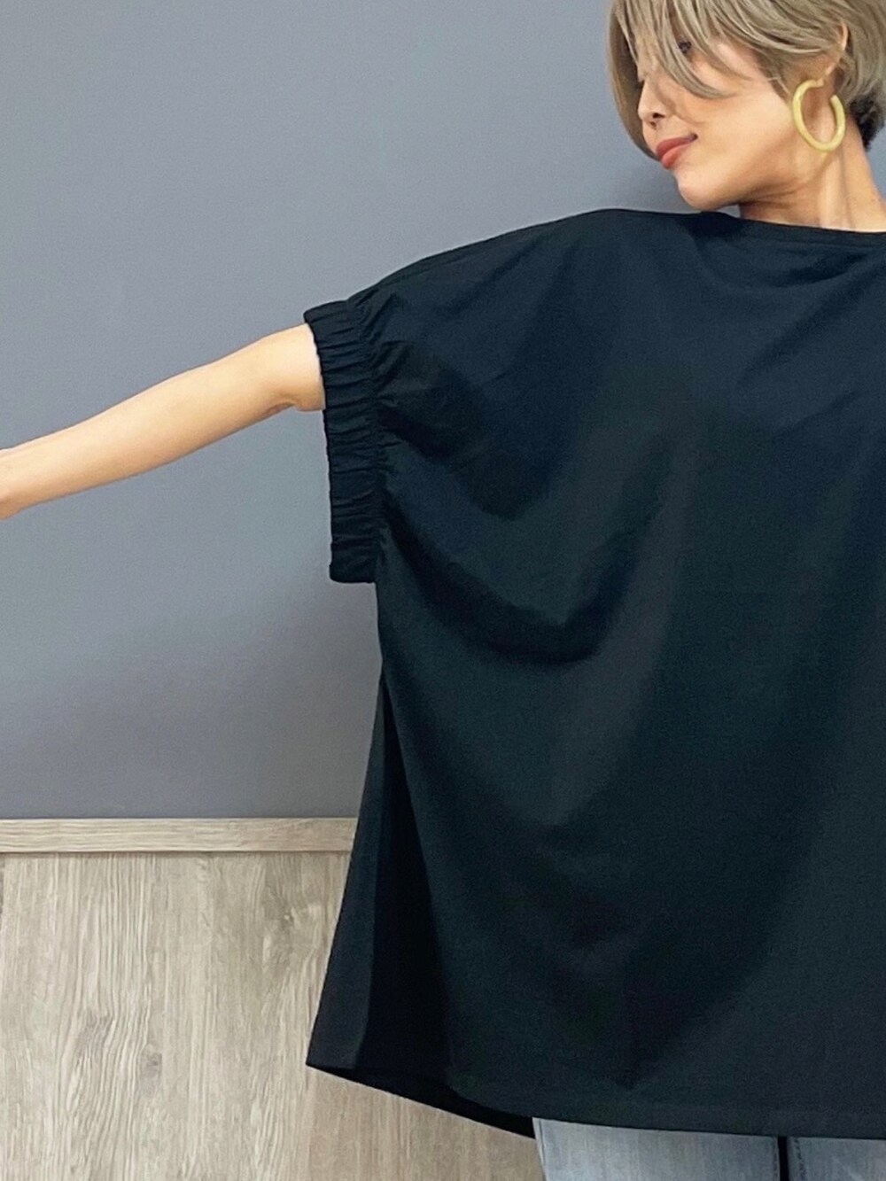 ブラック系のトップス、ブルー系のデニムパンツ、ブラック系のショルダーバッグを着用したレディースの夏コーディネートの2枚目の写真