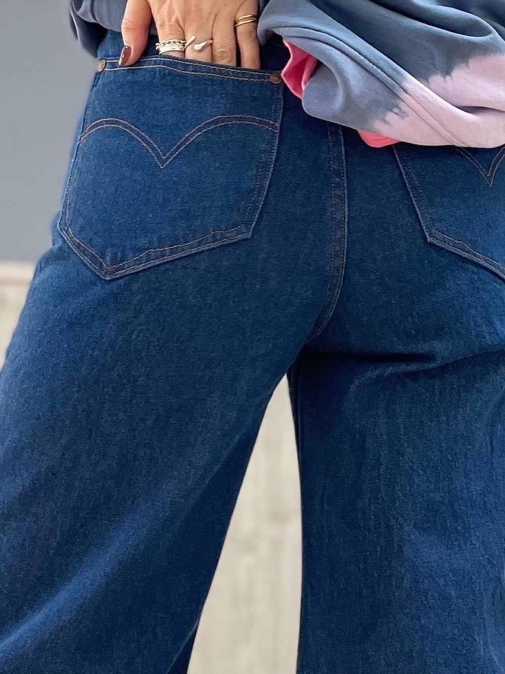 ブルー系のデニムパンツ、シルバー系のショルダーバッグ、パープル系のトップスを着用したレディースの春コーディネートの5枚目の写真