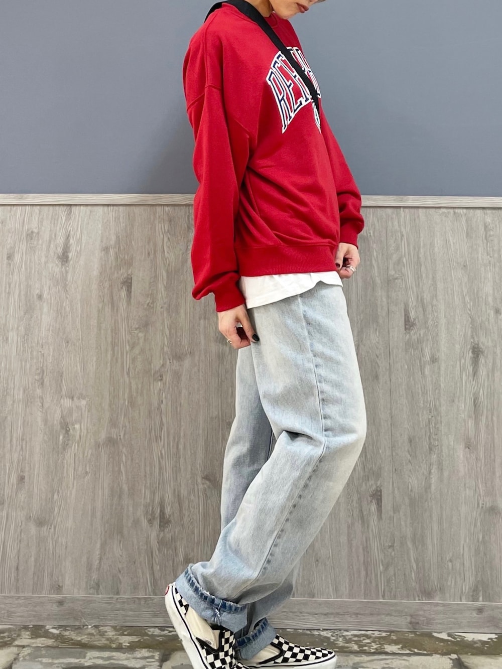 ブラック系のショルダーバッグ、レッド系のスウェット、ブルー系のデニムパンツを着用したレディースの春コーディネートの3枚目の写真