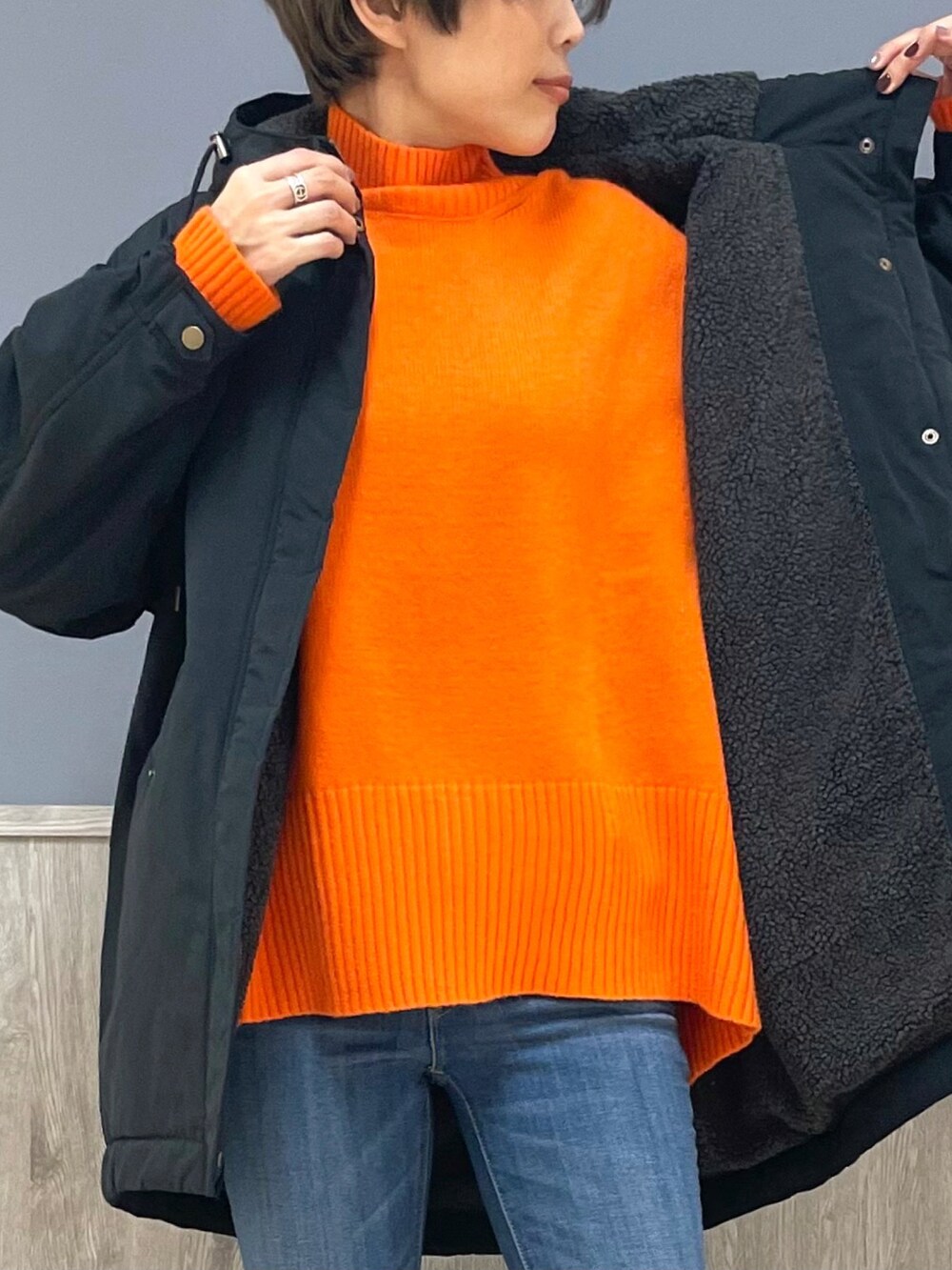 オレンジ系のニット/セーター、ブラック系のその他アウター、ベージュ系のトートバッグを着用したレディースの冬コーディネートの3枚目の写真