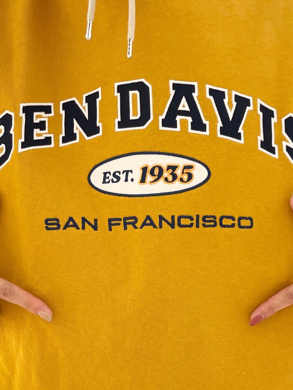 ブルー系のショルダーバッグ、イエロー系のTシャツ/カットソー、ベージュ系のパーカーを着用したレディースの冬コーディネートの5枚目の写真