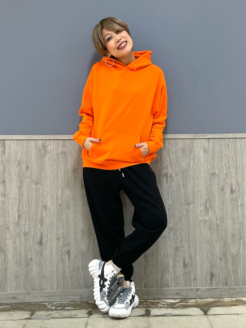 ブラック系のスウェットパンツ、オレンジ系のパーカー、ブラック系のボディバッグ/ウエストポーチを着用したレディースの冬コーディネートの4枚目の写真