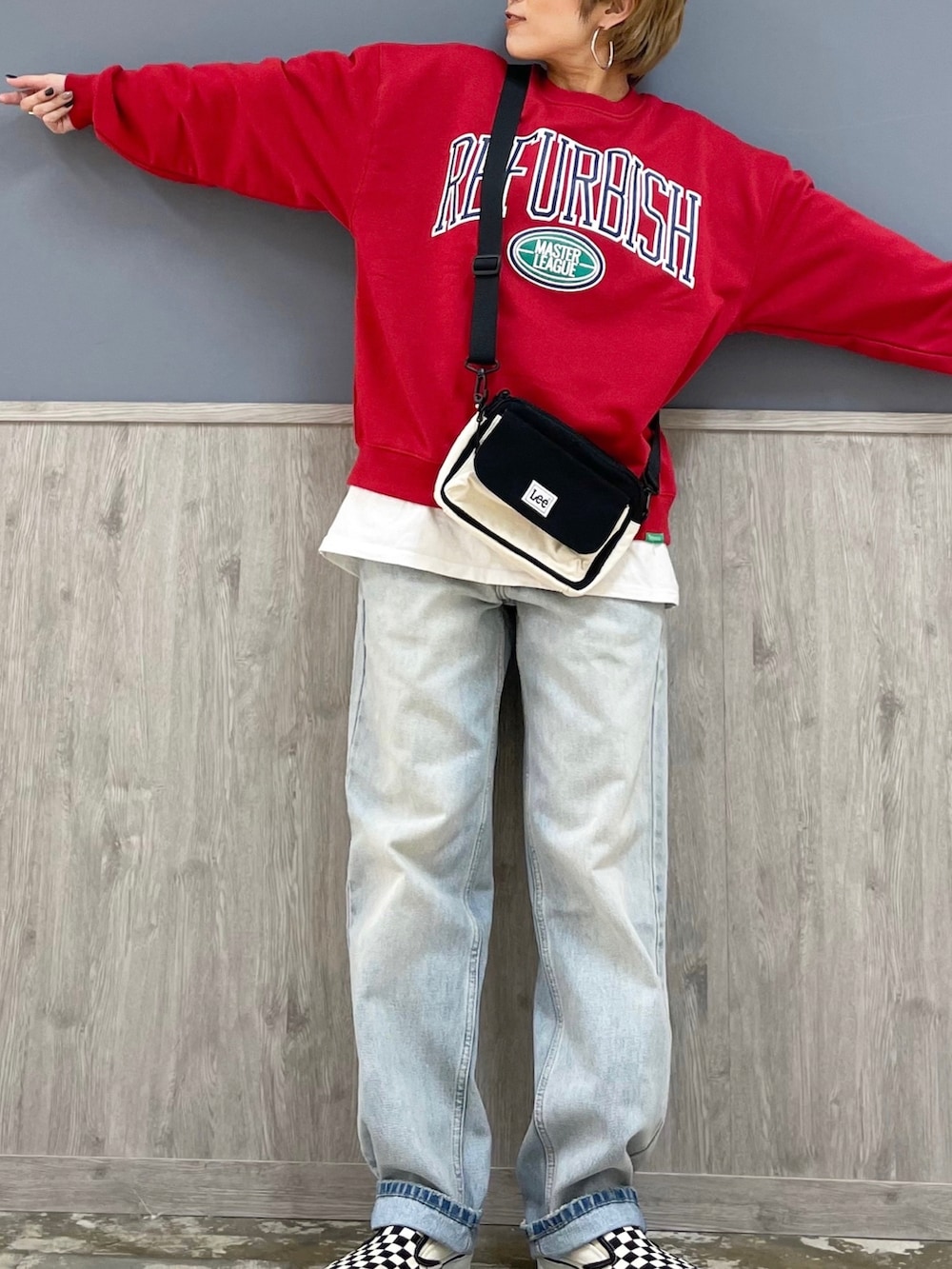 ブラック系のショルダーバッグ、レッド系のスウェット、ブルー系のデニムパンツを着用したレディースの春コーディネートの2枚目の写真