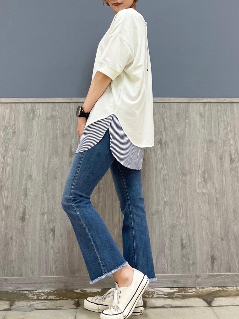 ブルー系のデニムパンツ、ホワイト系のトップス、ブルー系のタンクトップを着用したレディースの春コーディネートの2枚目の写真