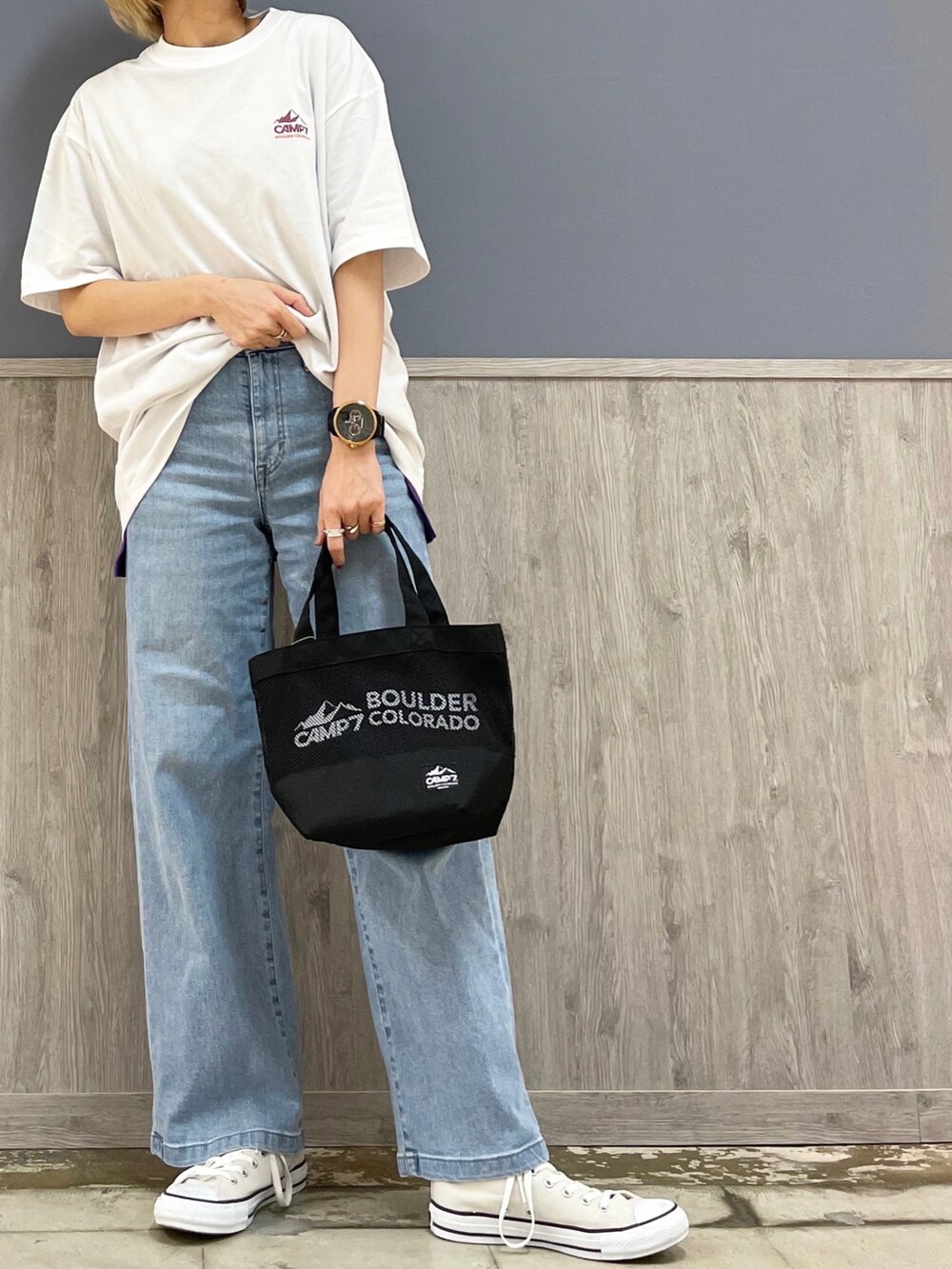 ブラック系のトートバッグ、ブルー系のデニムパンツ、ベージュ系のスニーカーを着用したレディースの春コーディネートの2枚目の写真