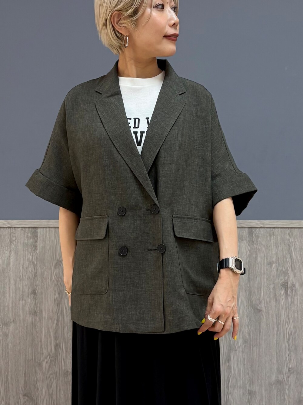 グレー系のテーラードジャケット、ホワイト系のTシャツ/カットソー、ブラック系のスカートを着用したレディースの夏コーディネートの2枚目の写真