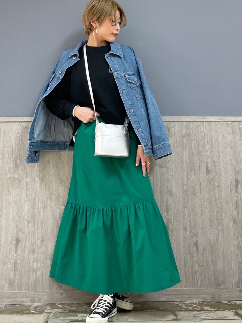 ブラック系のスニーカー、グリーン系のスカート、ブルー系のデニムジャケットを着用したレディースの春コーディネートの3枚目の写真