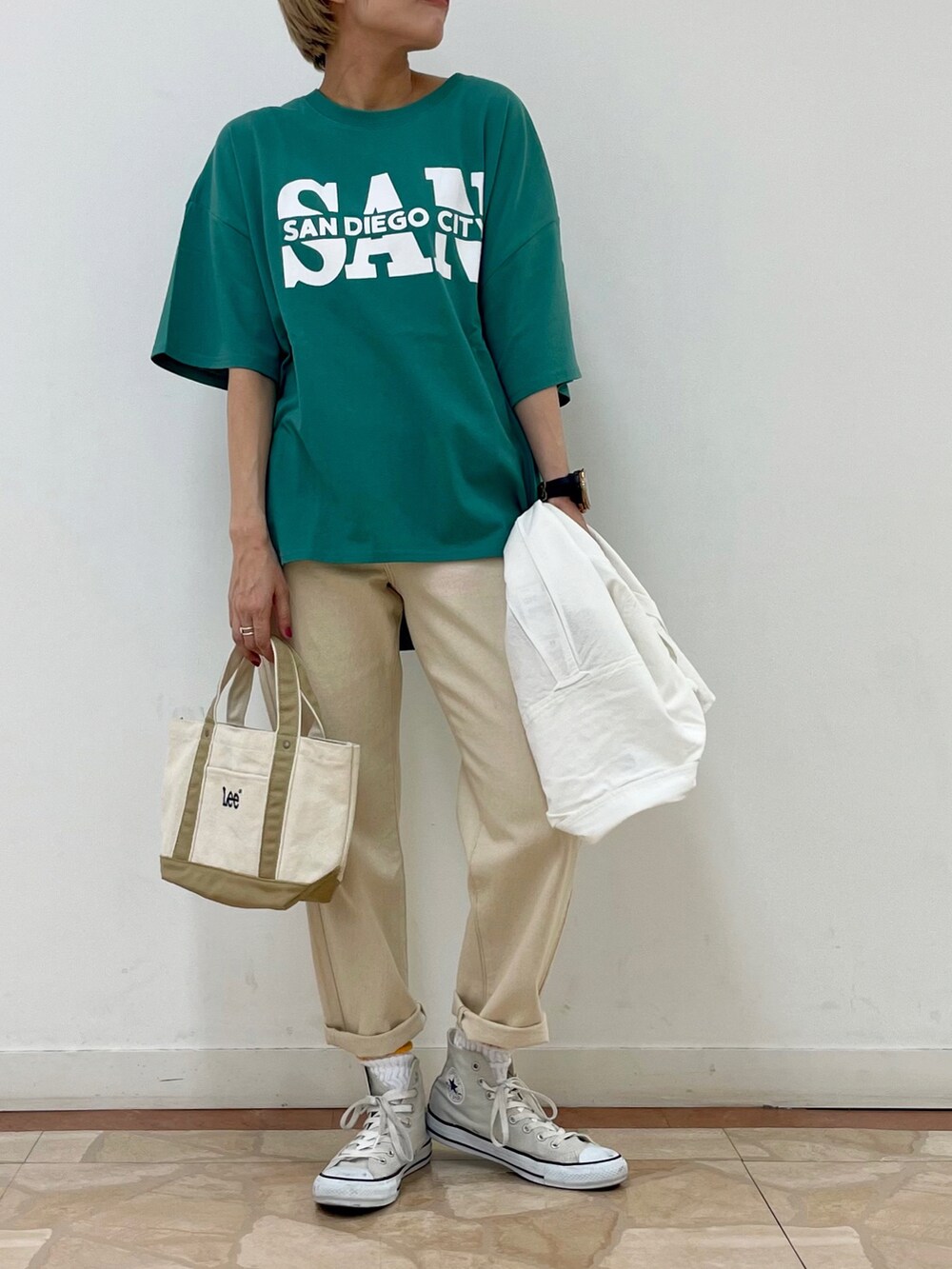 ホワイト系のデニムパンツ、グリーン系のTシャツ/カットソー、ベージュ系のトートバッグを着用したレディースの夏コーディネートの2枚目の写真