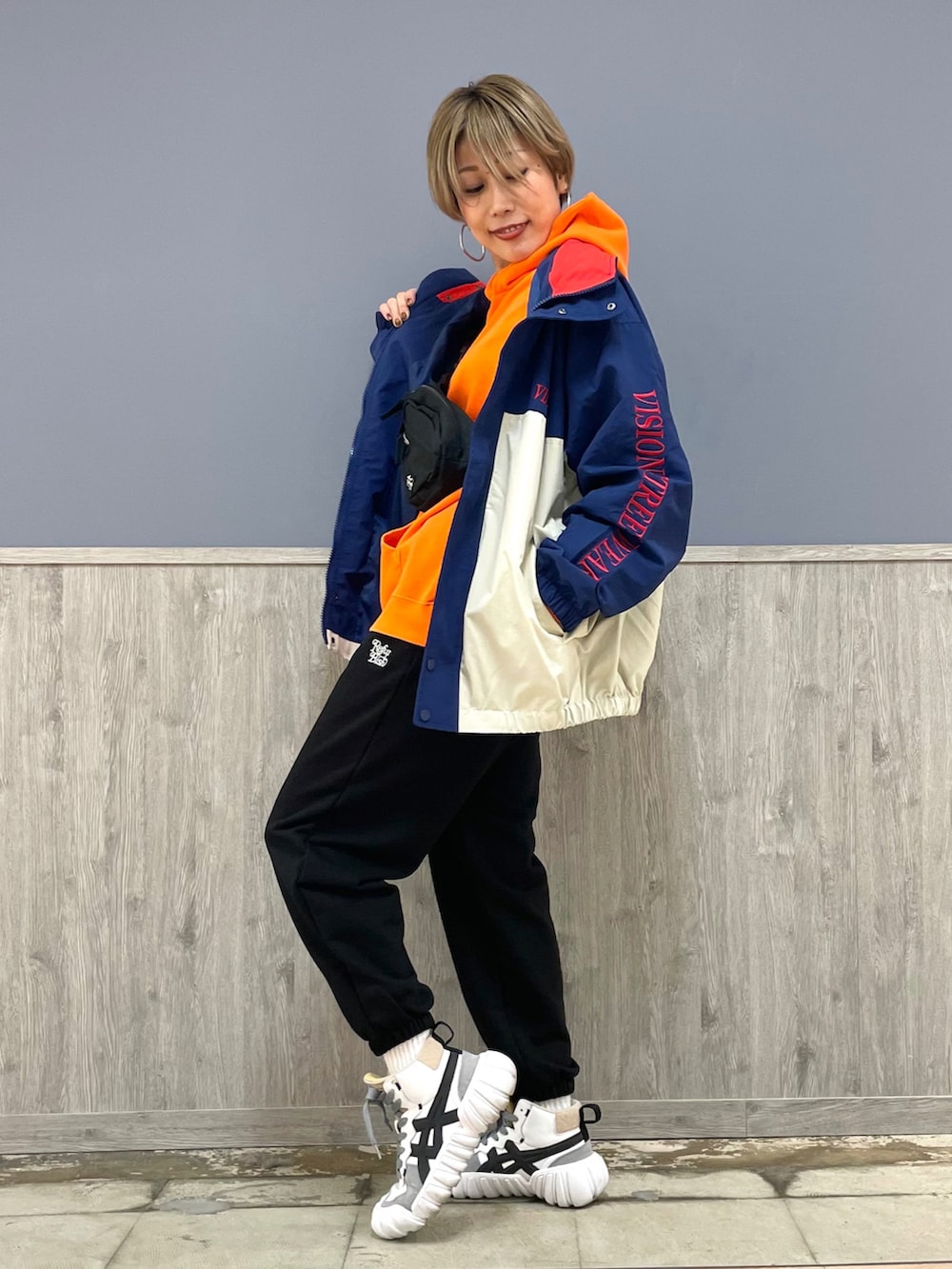 ブラック系のスウェットパンツ、オレンジ系のパーカー、ブラック系のボディバッグ/ウエストポーチを着用したレディースの冬コーディネートの2枚目の写真