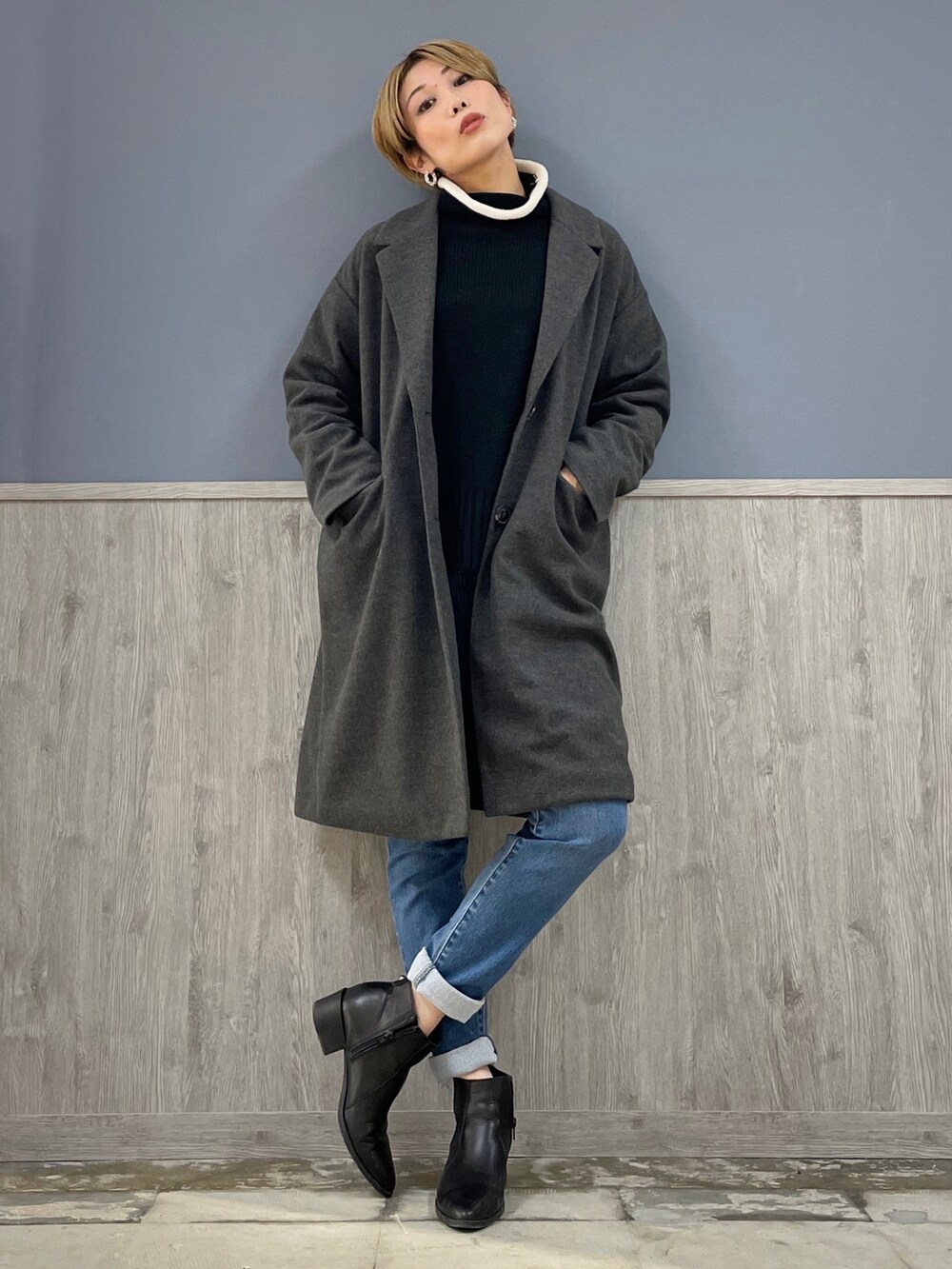 グレー系のチェスターコート、ブルー系のデニムパンツ、ブラック系のニット/セーターを着用したレディースの冬コーディネートの5枚目の写真