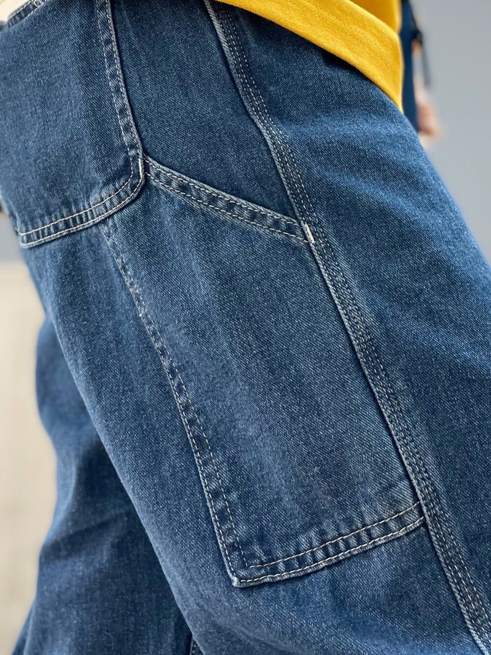 ブルー系のショルダーバッグ、イエロー系のTシャツ/カットソー、ベージュ系のパーカーを着用したレディースの冬コーディネートの4枚目の写真