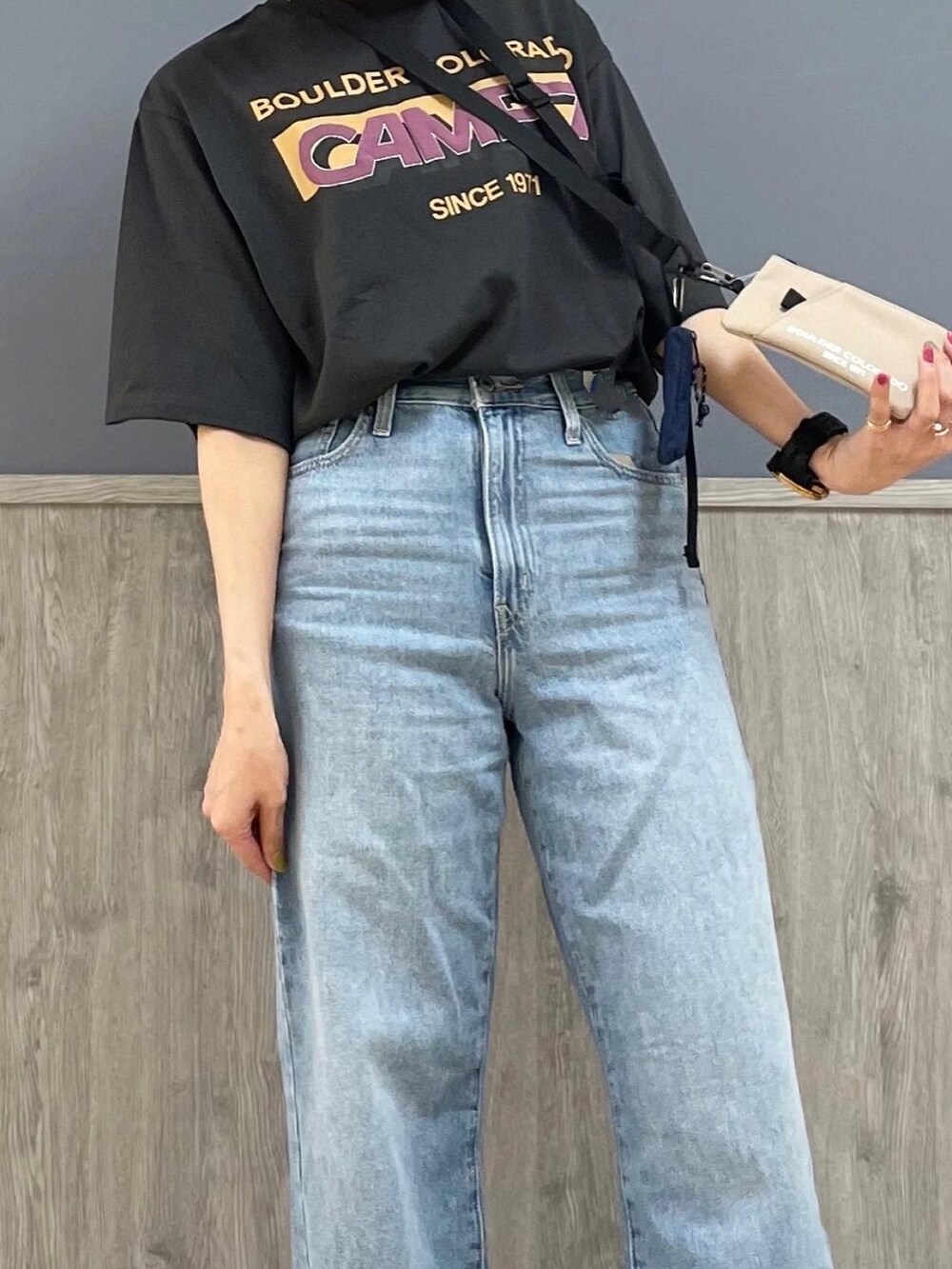 グレー系のTシャツ/カットソー、ベージュ系のショルダーバッグ、ブルー系のデニムパンツを着用したレディースの春コーディネートの2枚目の写真