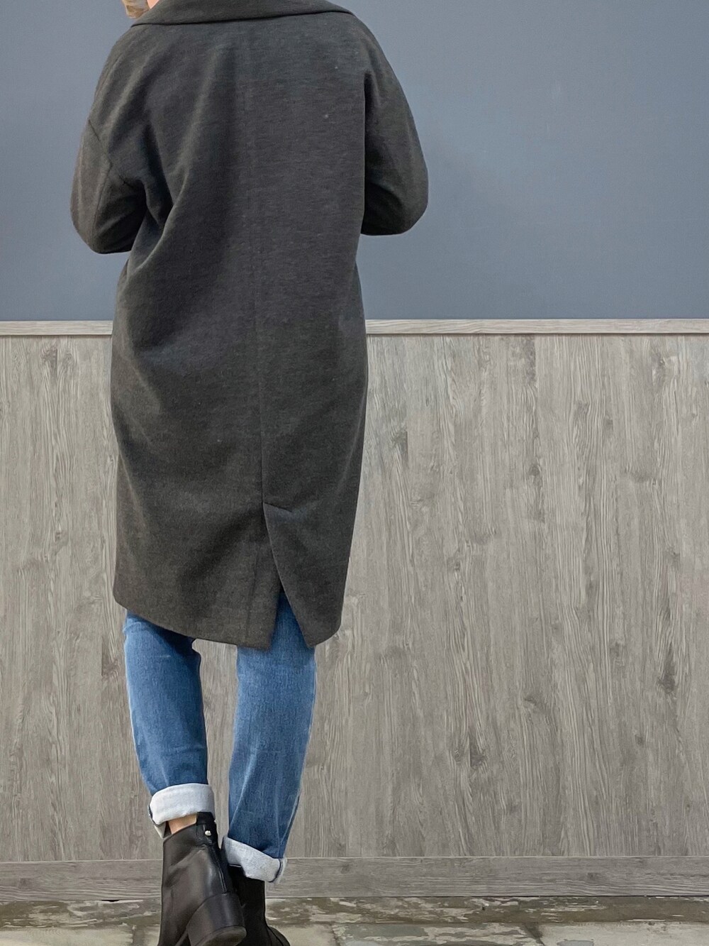 グレー系のチェスターコート、ブルー系のデニムパンツ、ブラック系のニット/セーターを着用したレディースの冬コーディネートの3枚目の写真