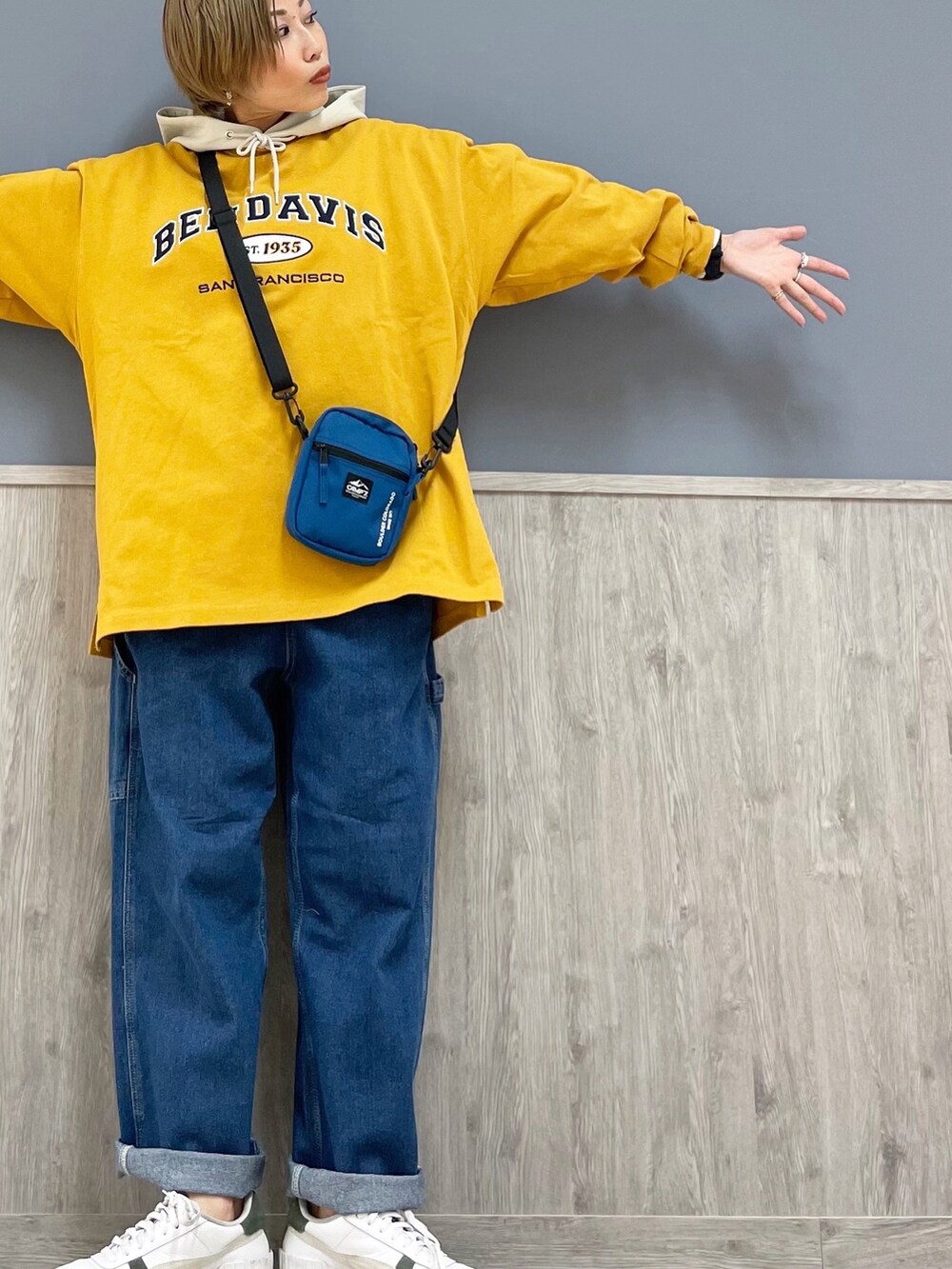 ブルー系のショルダーバッグ、イエロー系のTシャツ/カットソー、ベージュ系のパーカーを着用したレディースの冬コーディネートの2枚目の写真