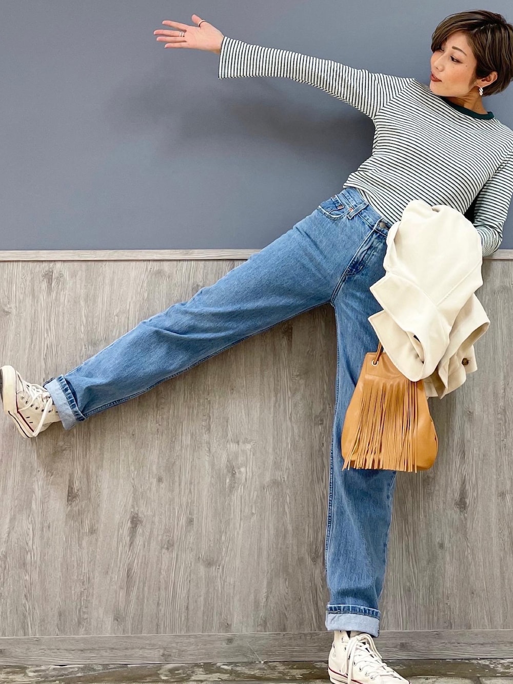 ブラウン系のショルダーバッグ、ホワイト系のシューズ、ブルー系のデニムパンツを着用したレディースの冬コーディネートの2枚目の写真