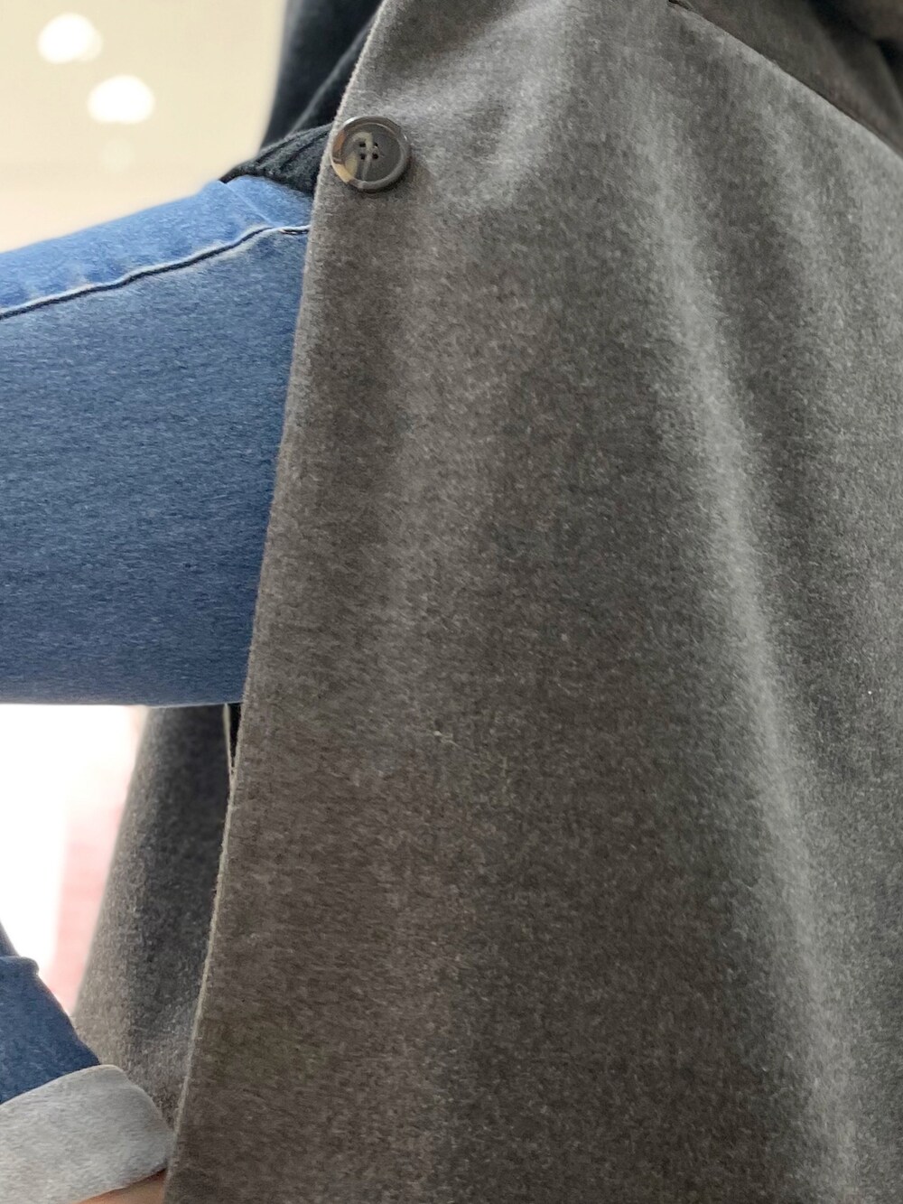 グレー系のチェスターコート、ブルー系のデニムパンツ、ブラック系のニット/セーターを着用したレディースの冬コーディネートの4枚目の写真