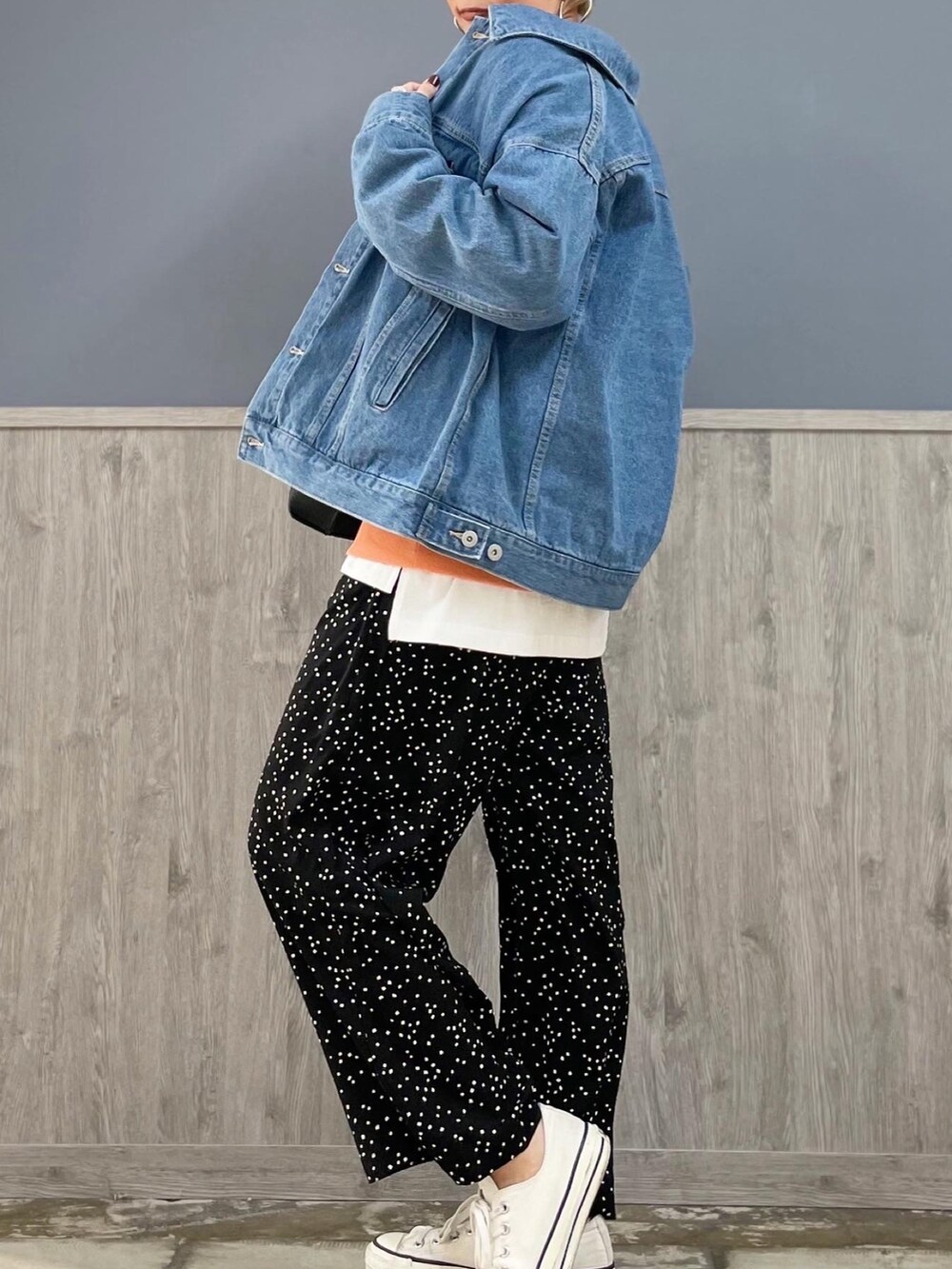 ブラック系のその他パンツ、オレンジ系のスウェット、ブルー系のデニムジャケットを着用したレディースの春コーディネートの2枚目の写真