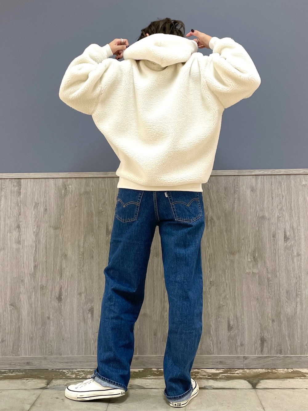 ブルー系のデニムパンツ、ブラウン系のショルダーバッグ、ホワイト系のパーカーを着用したレディースの冬コーディネートの3枚目の写真